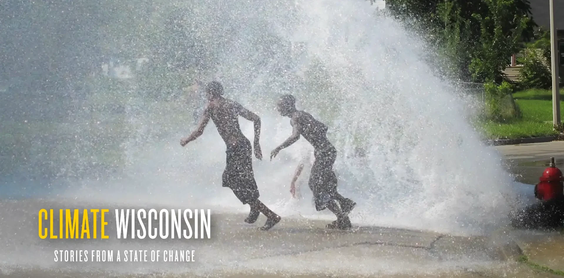 Two youths cooling off in the water from a hydrant