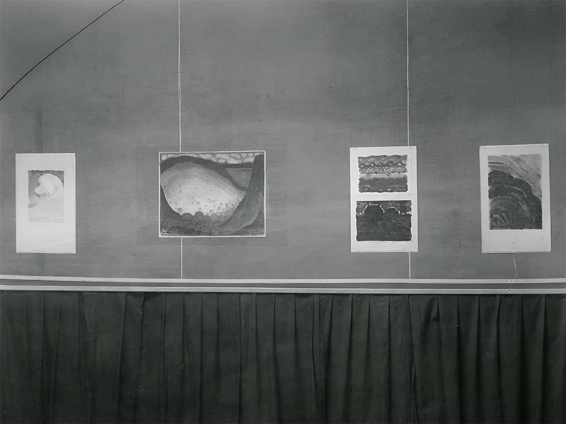 A black and white photograph of four paintings by Georgia O'Keeffe hanging in a gallery.