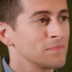 Close-up of man with short dark hair in a neutral expression, facing slightly right.