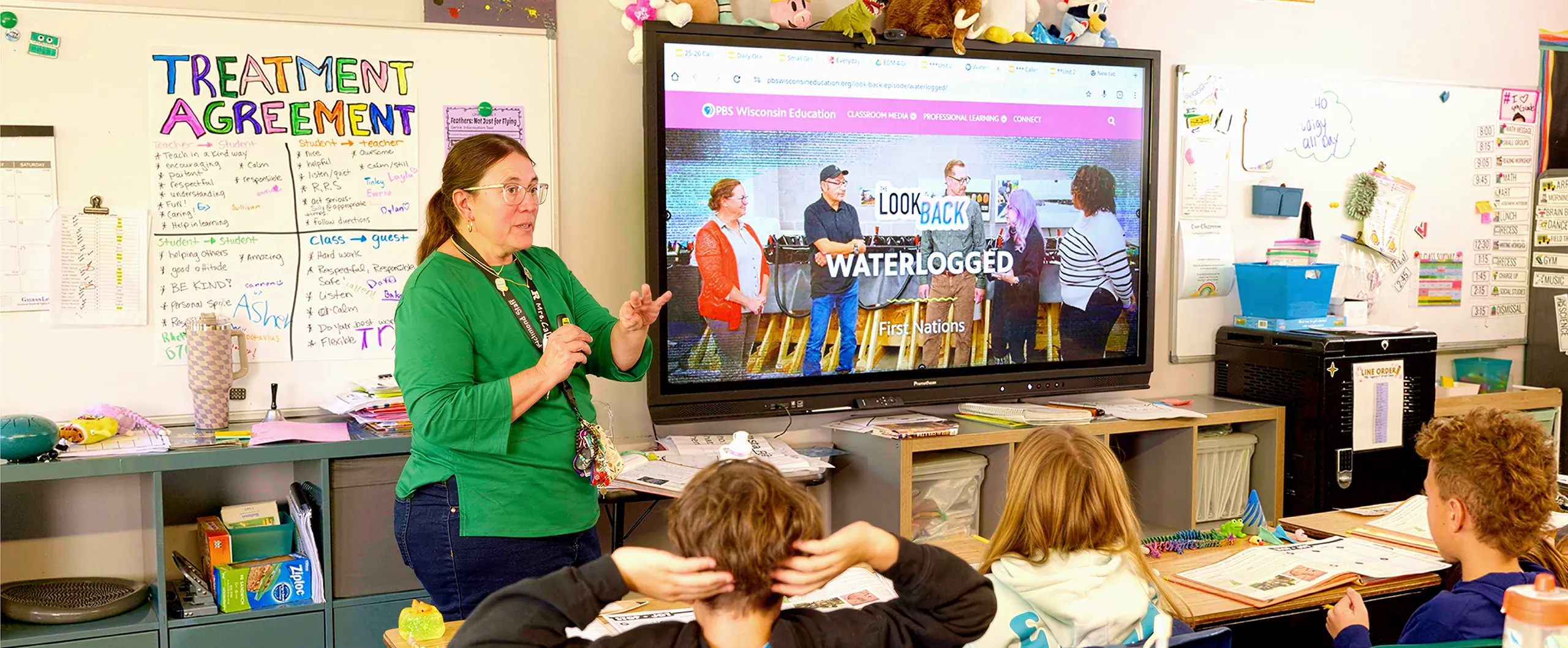 And educator presents The Look Back, a video series, on a large screen at the front of a classroom