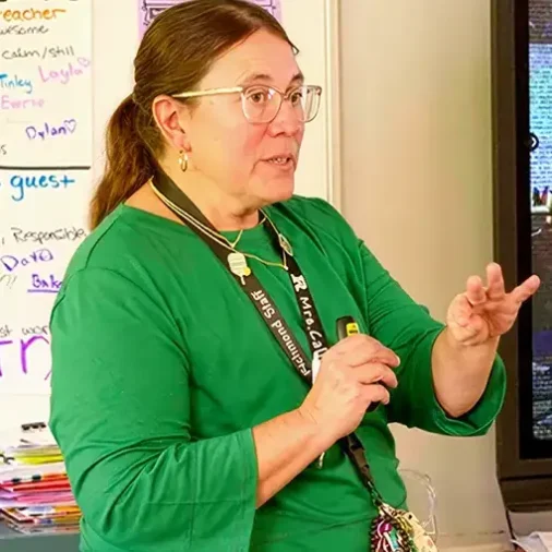 Educator standing at the front of a classroom teaching students