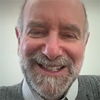 Jonathan Patz laughs broadly during a video interview, wearing a gray cable-knit sweater against a light background.