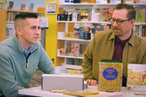 Two people at a table with vintage Golden Books in a bookstore with yellow walls