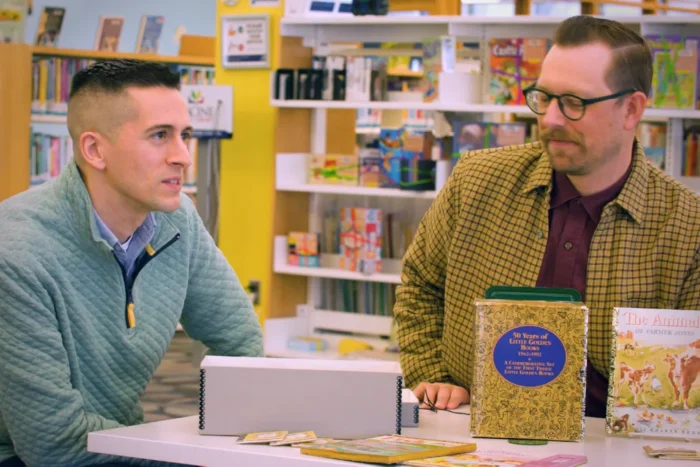 Two people at a table with vintage Golden Books in a bookstore with yellow walls
