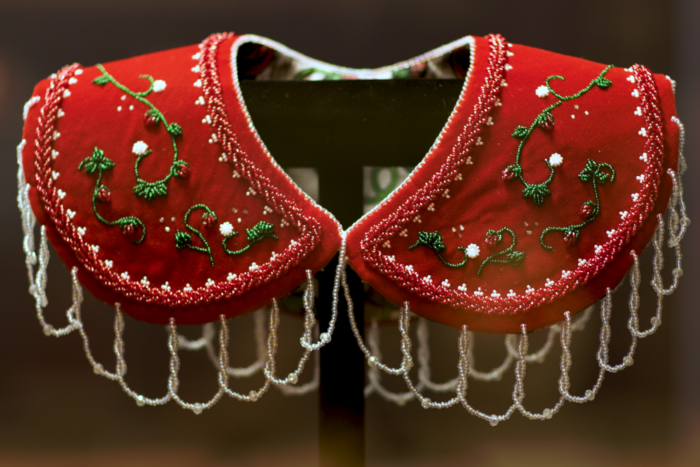 Red velvet collar beaded with green vines, strawberries and white flowers, edged with loops of clear beaded fringe.