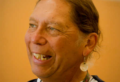 Person laughing, wearing a round shell earring.