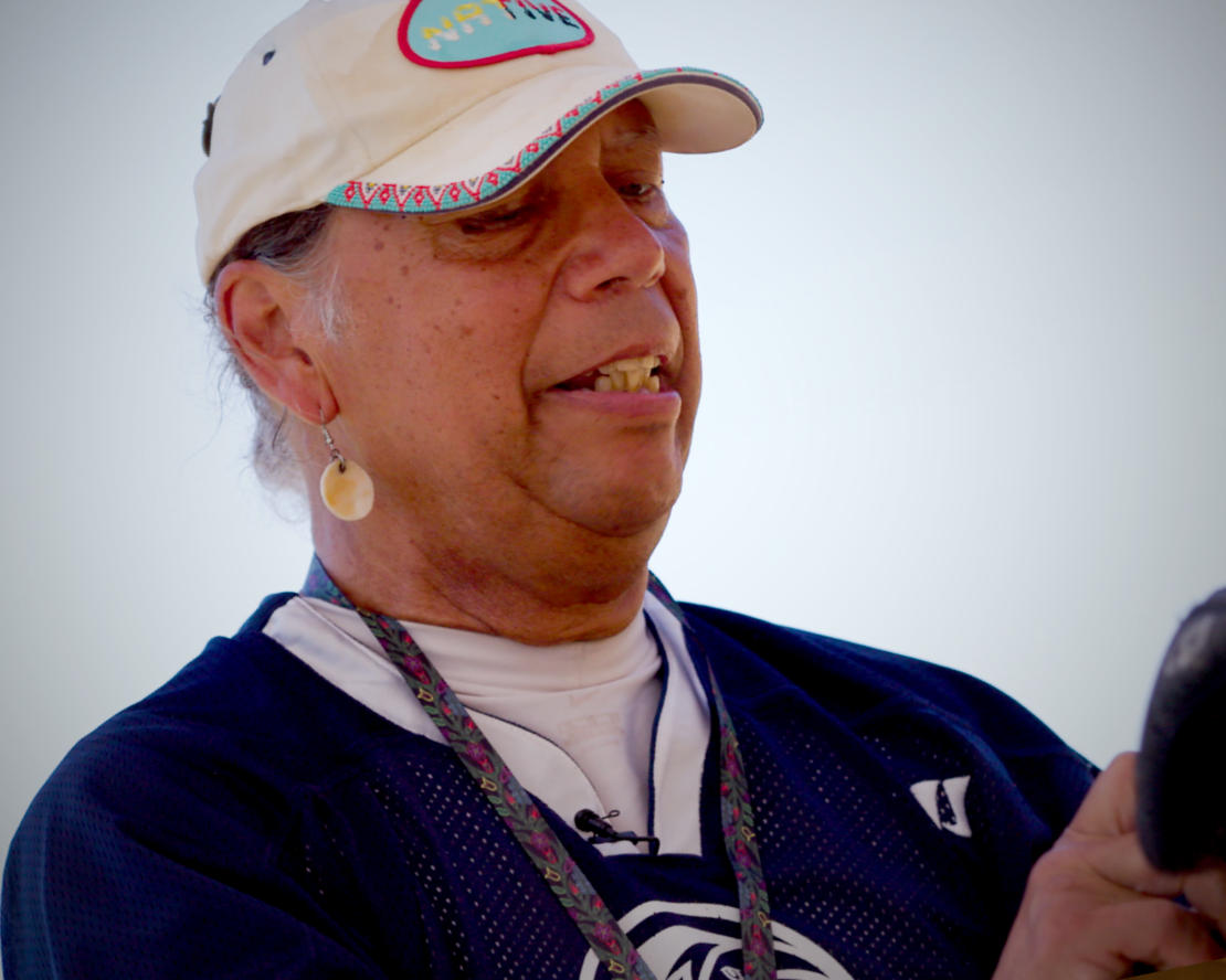 A man in a white baseball hat, wearing a shell earring.